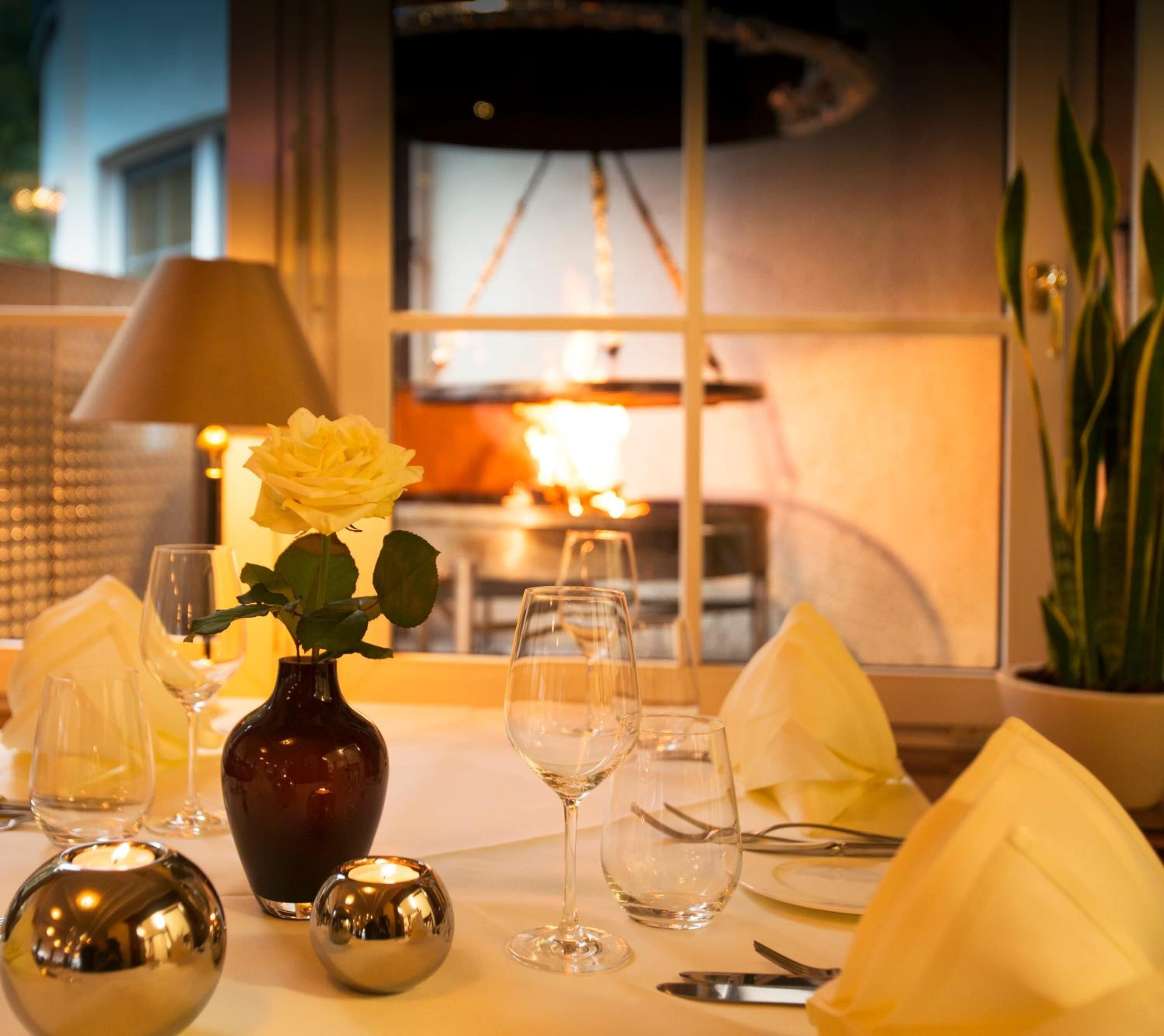 A table set for dining with a vase of flowers, wine glasses, and a candle.