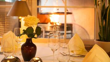 A table set for dining with a vase of flowers, wine glasses, and a candle.