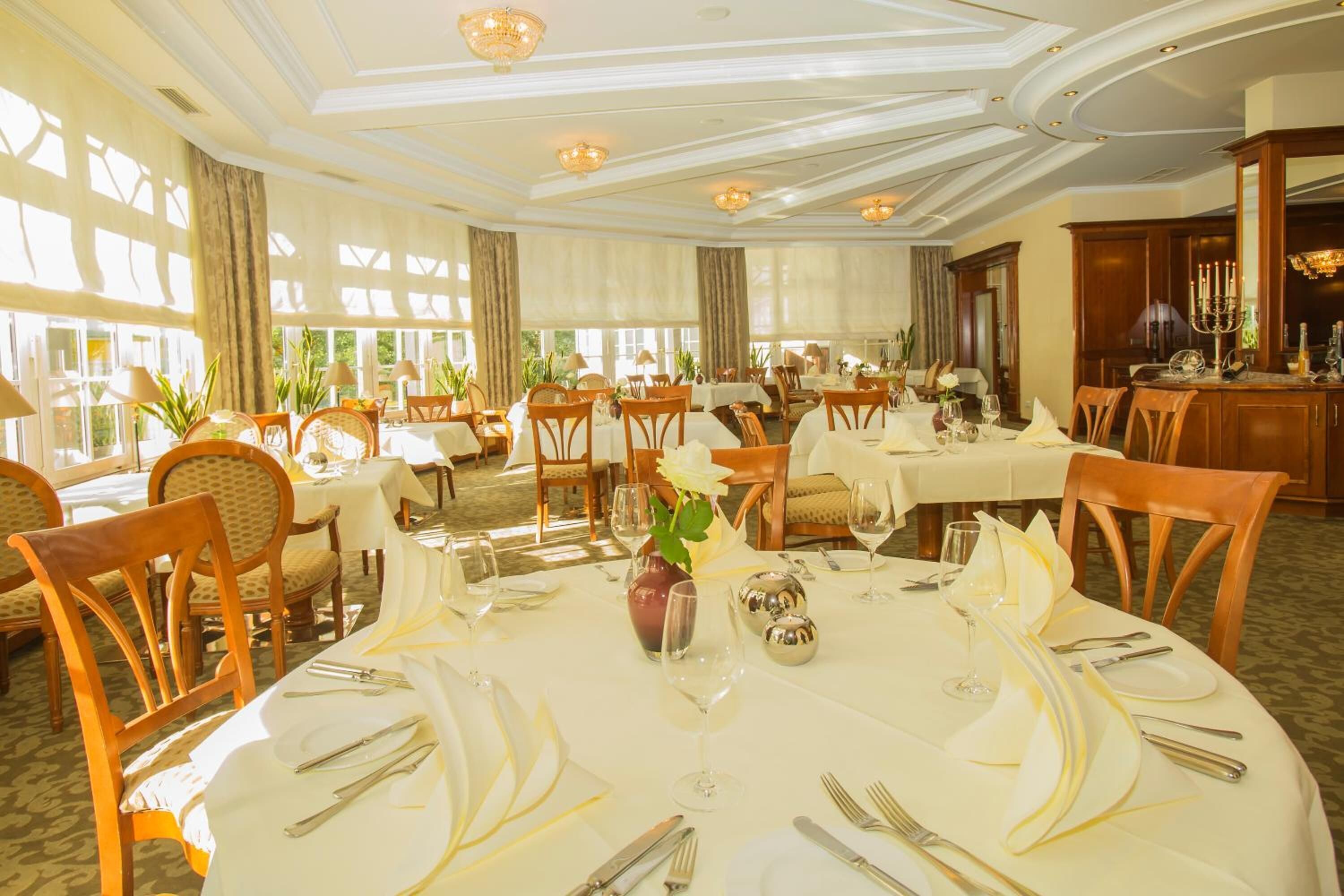 Una sala de dinar formal amb taules rodones, tovallons blancs i cadires de fusta.