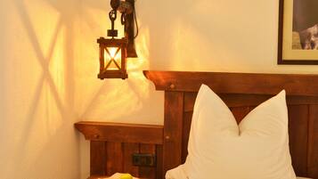 A bedroom with a wooden headboard, a bedside table with a lamp, and a framed picture on the wall.