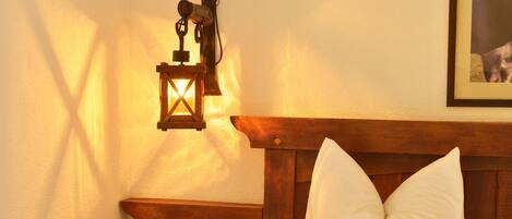 A bedroom with a wooden headboard, a bedside table with a lamp, and a framed picture on the wall.