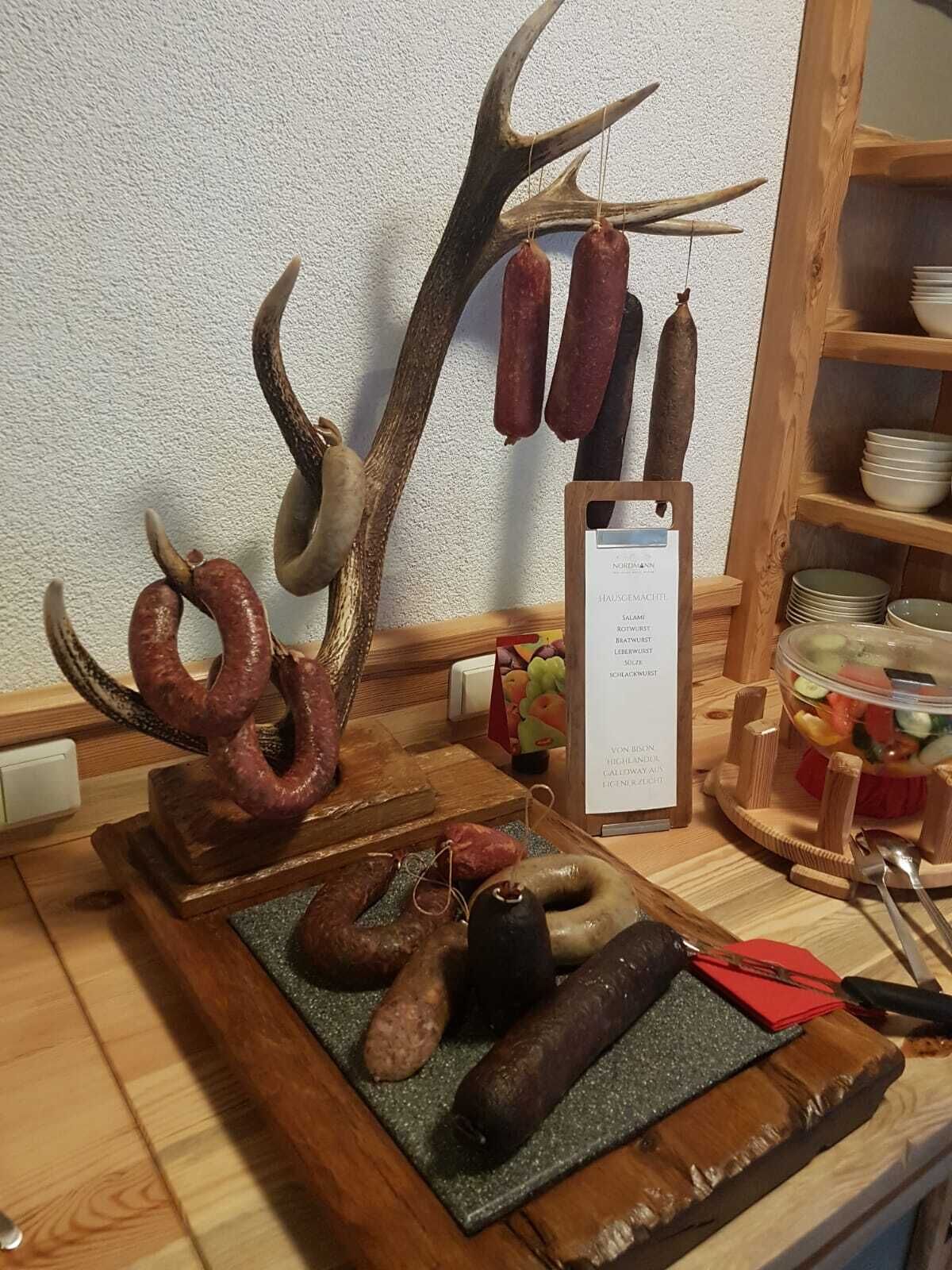 A wooden display with various types of sausages and a sign listing menu items.