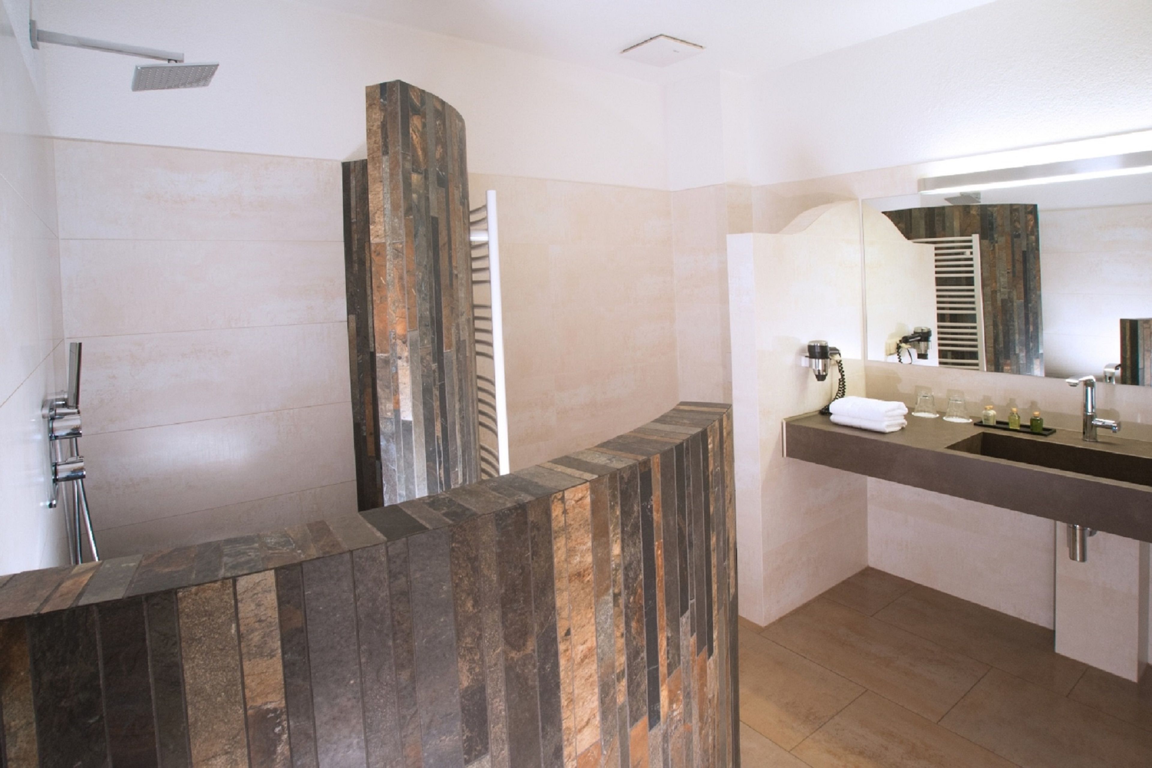 Een moderne badkamer met een douche, een wastafel met spiegel en een wasbak.