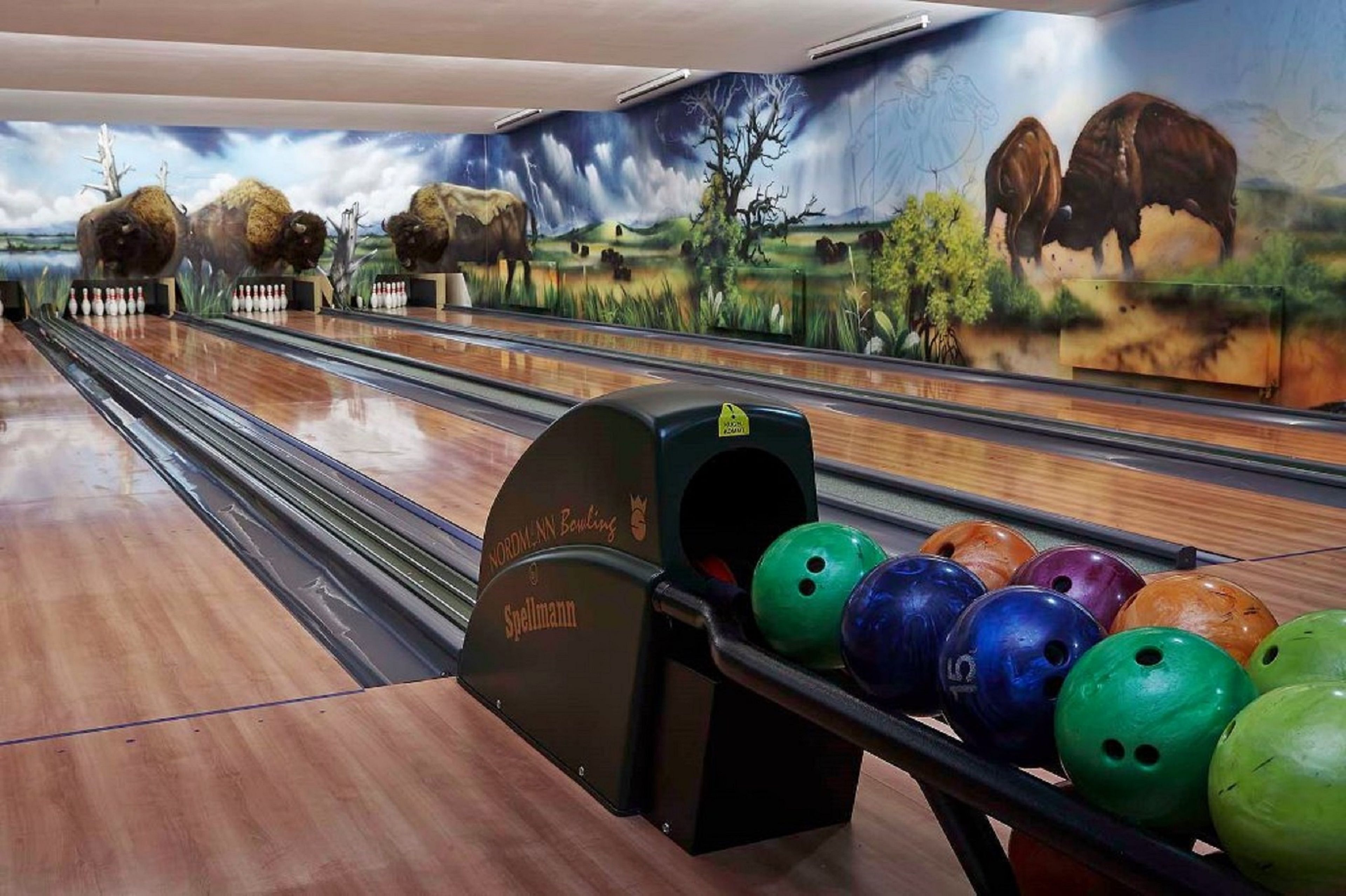 Eine Kegelbahn mit Wandgemälde von Bisons und einer Spellingman-Bowlingbahn.
