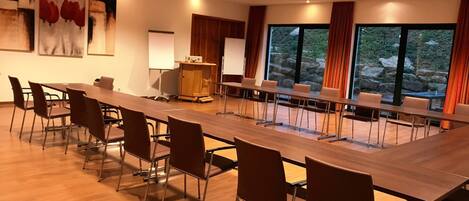 A conference room with a long table and chairs, a projector, and a whiteboard.