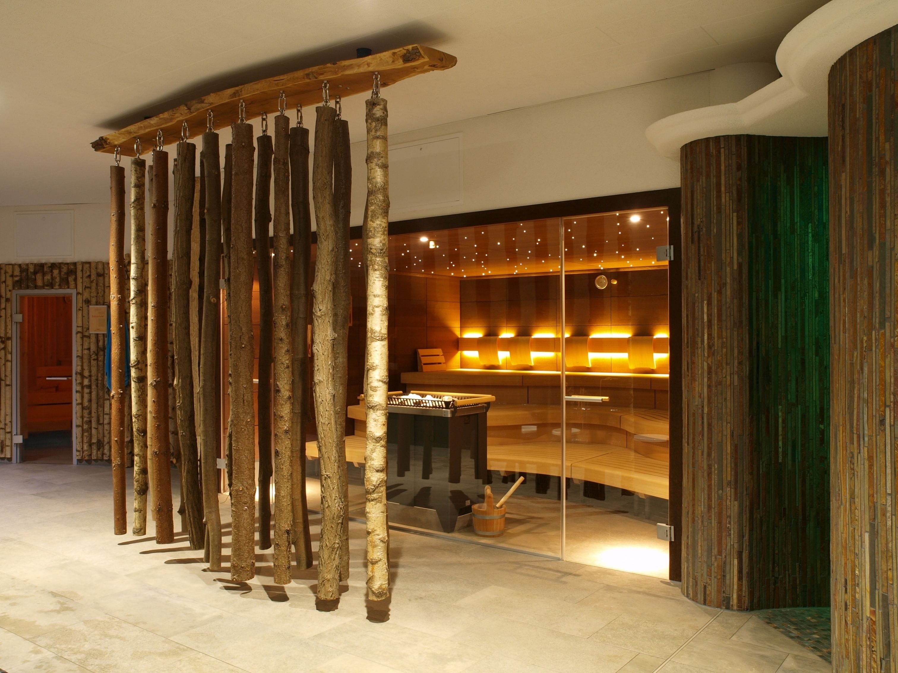 Un interior moderno con una instalación de madera, una zona de estar con separador de vidrio y un mostrador de recepción.