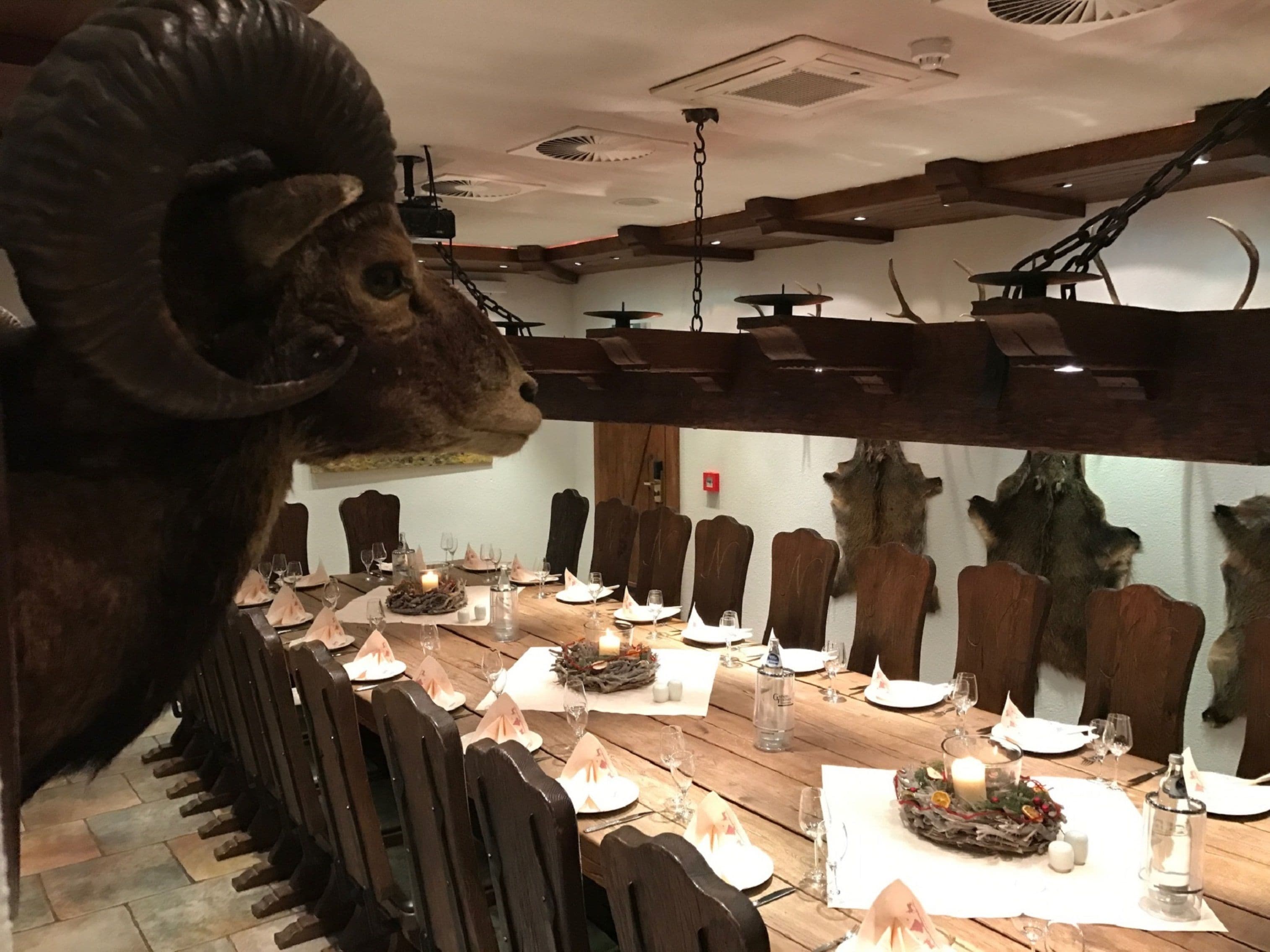 Un comedor con una larga mesa de madera dispuesta para una comida, rodeado de sillas de madera.