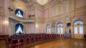 A grand hall with ornate architecture, a chandelier, and rows of red chairs. - Priska Heritage Rooms (Split)
