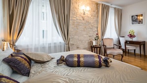 A hotel room with a bed, curtains, a stone wall, a desk, and a chair. - Priska Heritage Rooms (Split)
