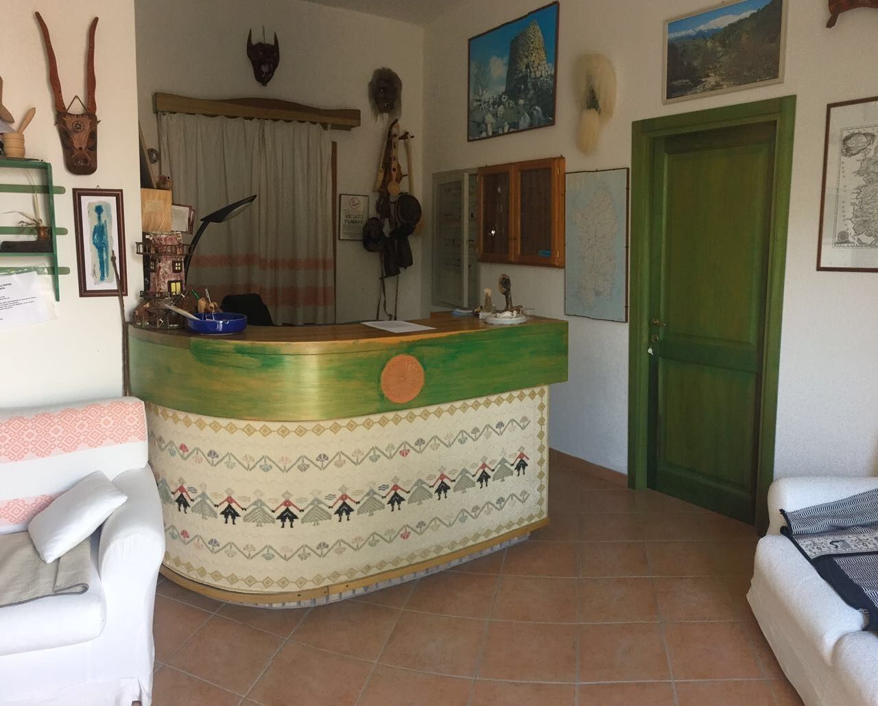A room with a green and beige patterned counter, white sofas, and a green door.