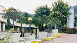 Entrada de hotel com uma estátua, degraus que levam ao edifício e um sinal indicando comodidades como restaurante e bar de lounge.