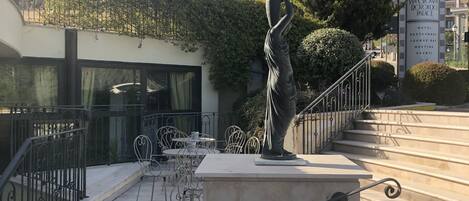 Una estatua sobre un pedestal en un patio con escalones que conducen a un edificio.