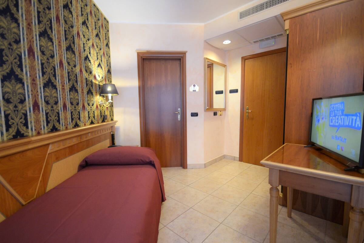 Ein Hotelzimmer mit einem Bett, einem Fernseher, einem Holzschrank und einem Spiegel.