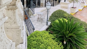 Um pátio com uma fonte, áreas de estar ao ar livre e vista para os edifícios e colinas ao redor.