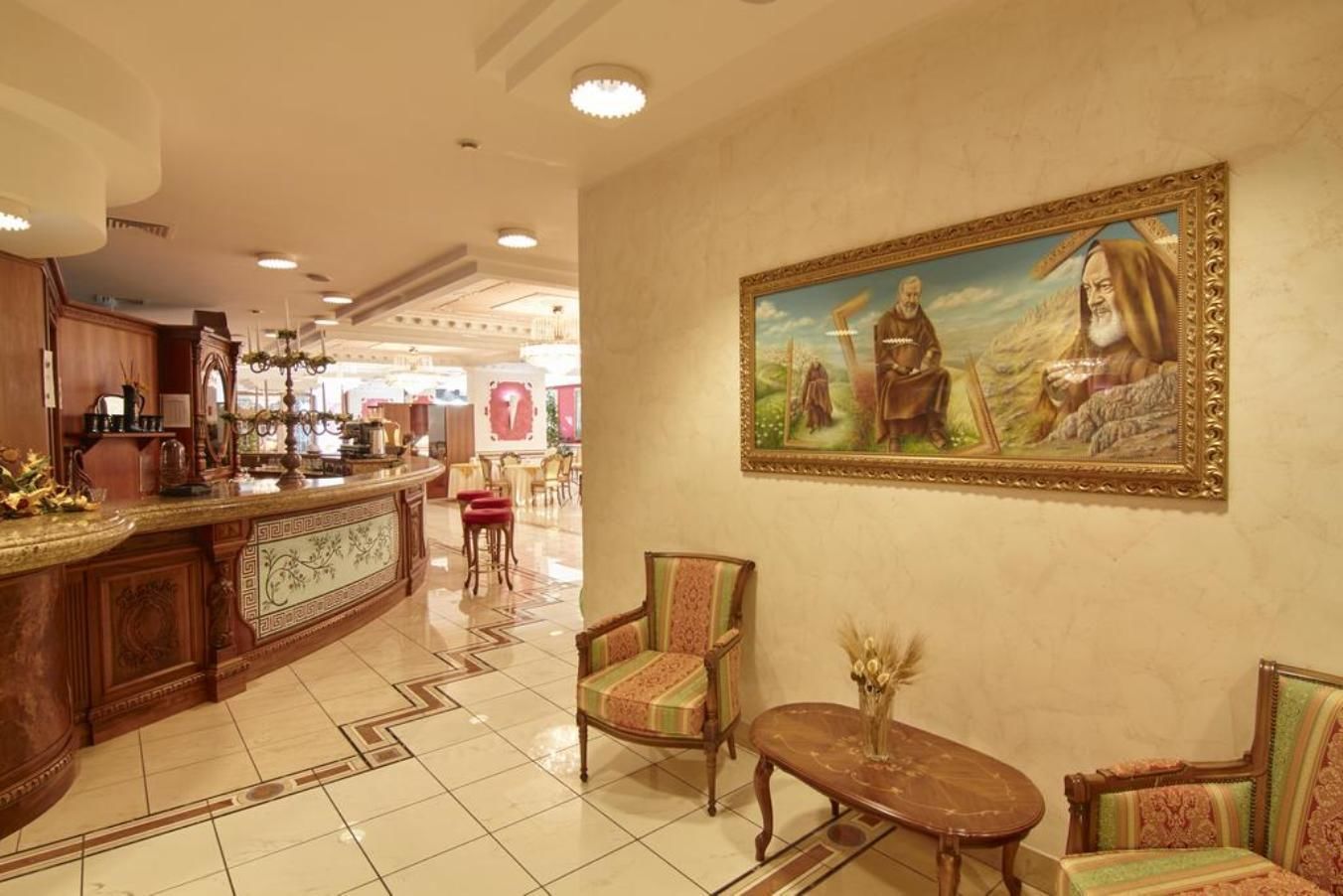 A lobby with a reception desk, seating area, and a large painting on the wall.