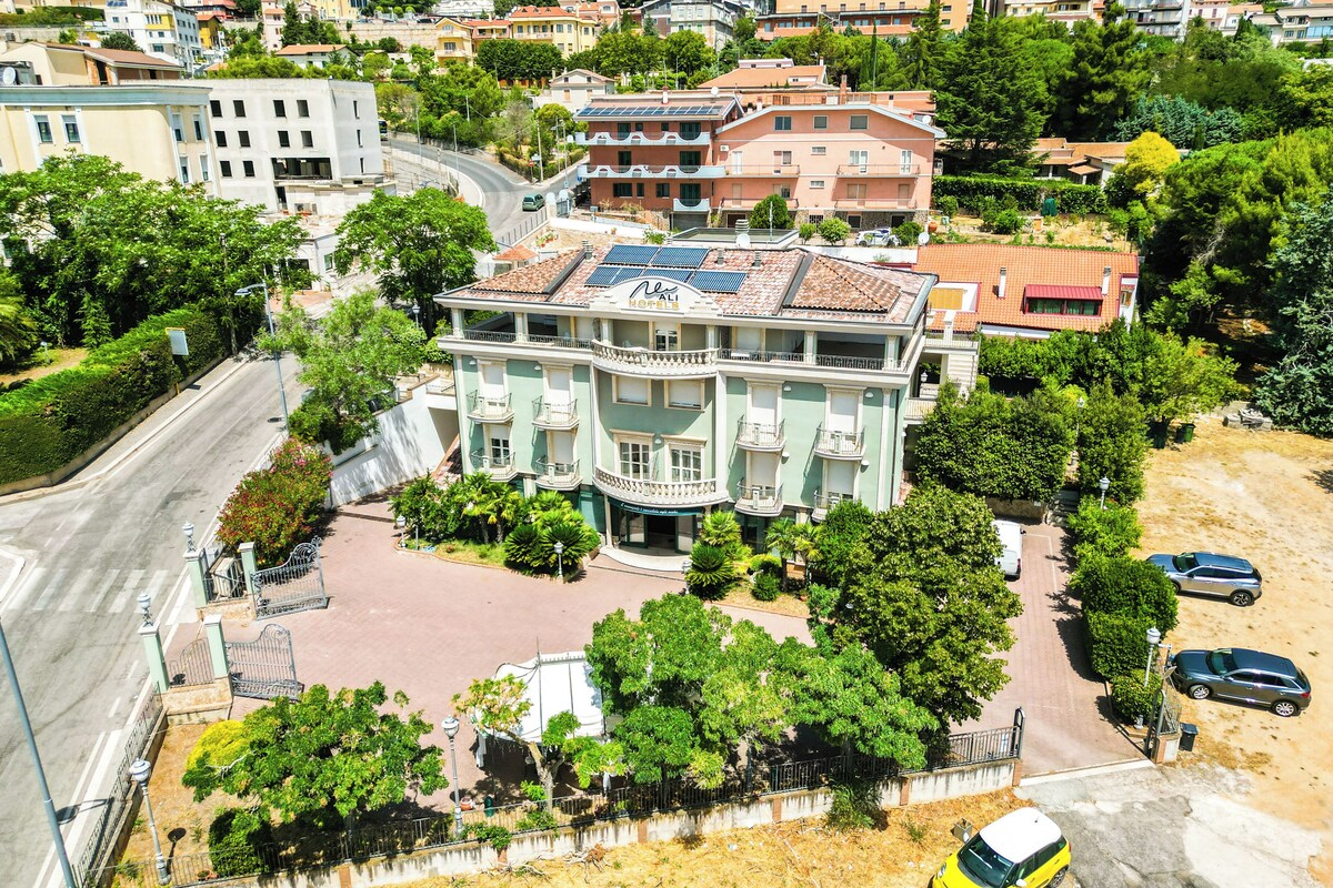 Ein mehrstöckiges Hotel mit einem zentralen Innenhof, umgeben von üppiger Bepflanzung, direkt an einer Straße gelegen.