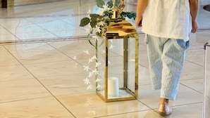 Criança caminhando em um hall amplo, com um abajur de vidro decorativo e piso de azulejos.