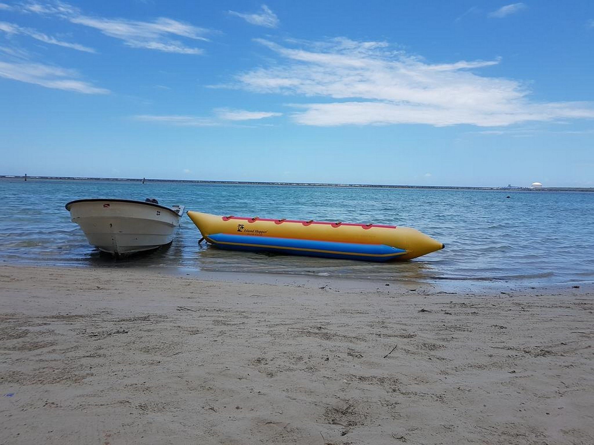 Ein Boot an einem sandigen Strand mit ruhigem Wasser und blauem Himmel.