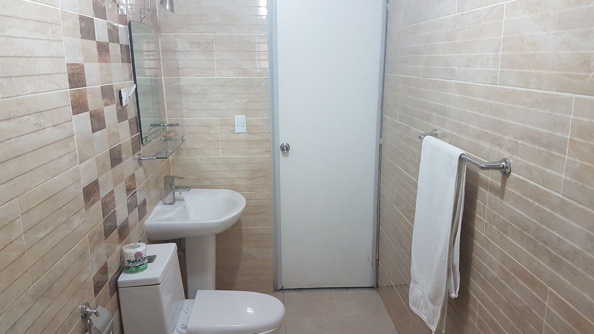 Un baño pequeño con inodoro, lavabo y perchero para toallas.