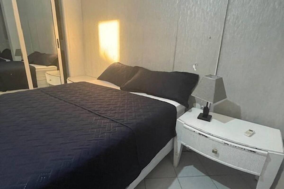 Un dormitorio con una cama, una mesita de noche, una lámpara, un espejo y una puerta corredera.