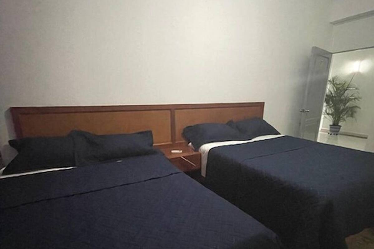 Una habitación de hotel con dos camas individuales, cabeceros de madera y una mesita de noche entre ellas.
