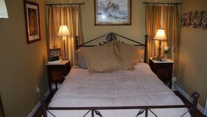 A bedroom with a bed, two bedside tables, a nightstand, a painting on the wall, and curtains. - Turner Falls (Davis)