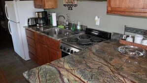 A kitchen with a granite countertop, stainless steel appliances, wooden cabinets, and a backsplash. - Turner Falls (Davis)
