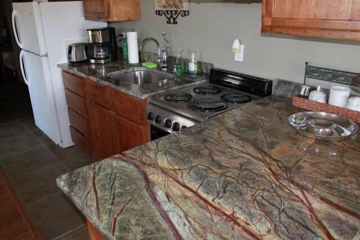 A kitchen with a granite countertop, stainless steel appliances, wooden cabinets, and a backsplash.
