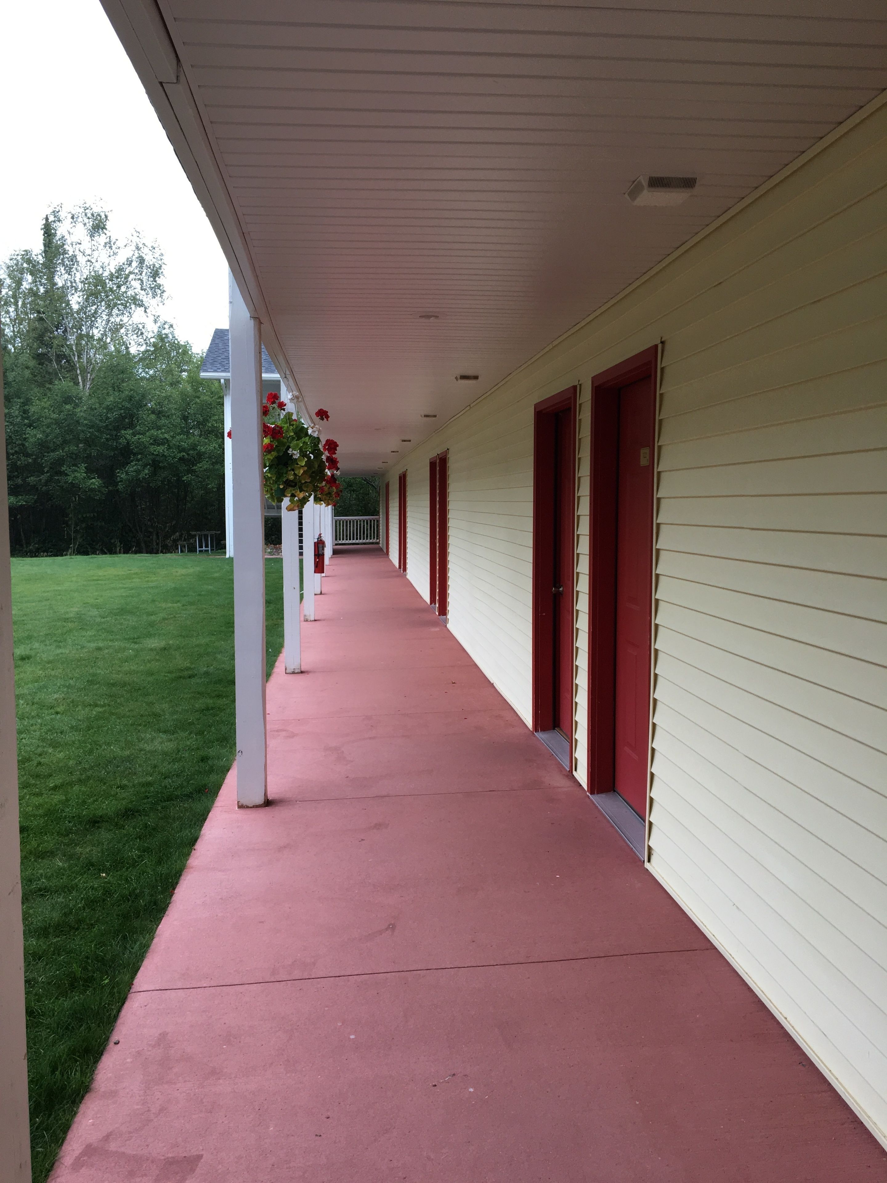 A covered porch with a red floor, white pillars, and red doors.