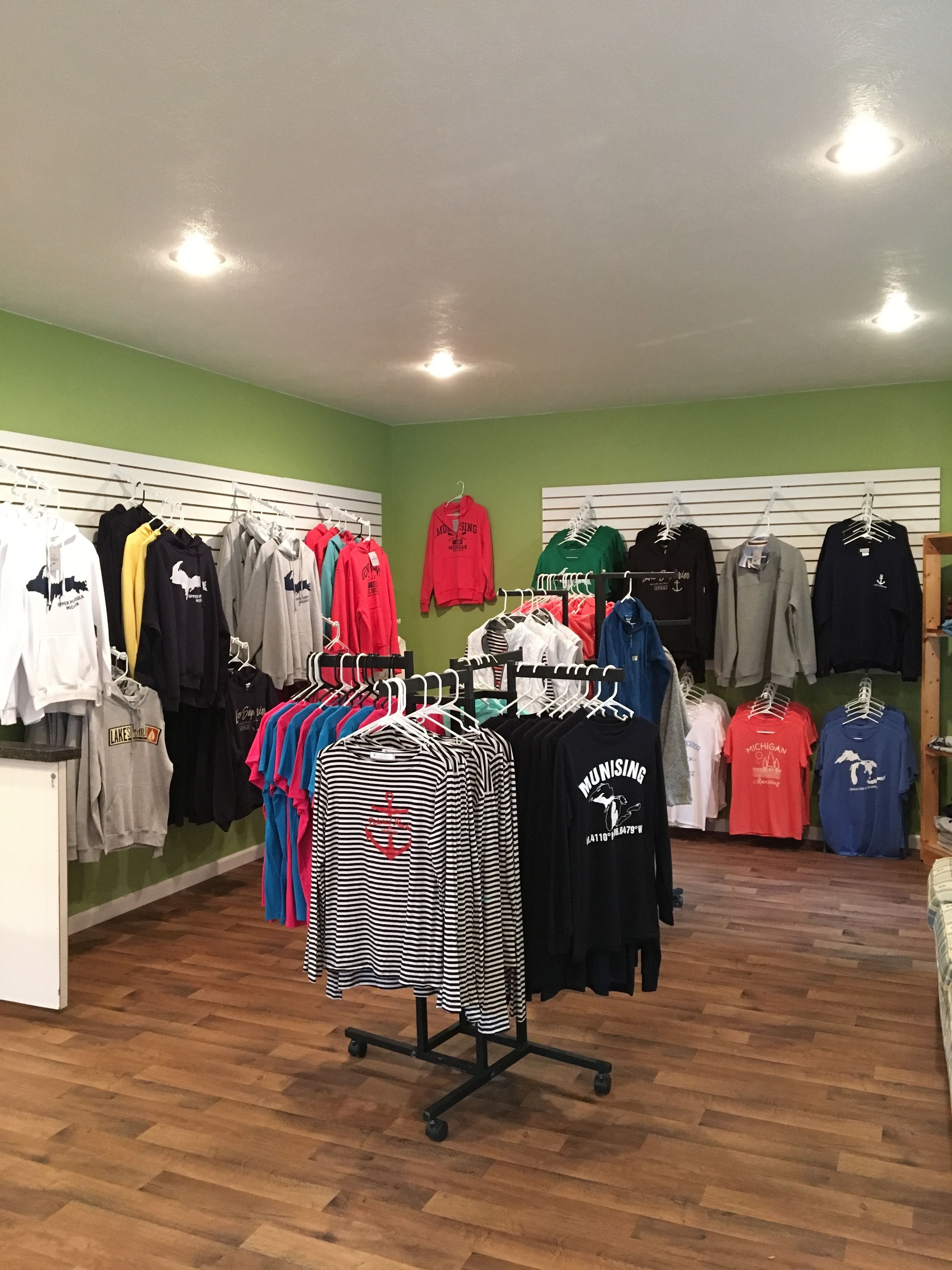 A clothing store with various garments on display, including t-shirts and hoodies, arranged on racks and shelves.
