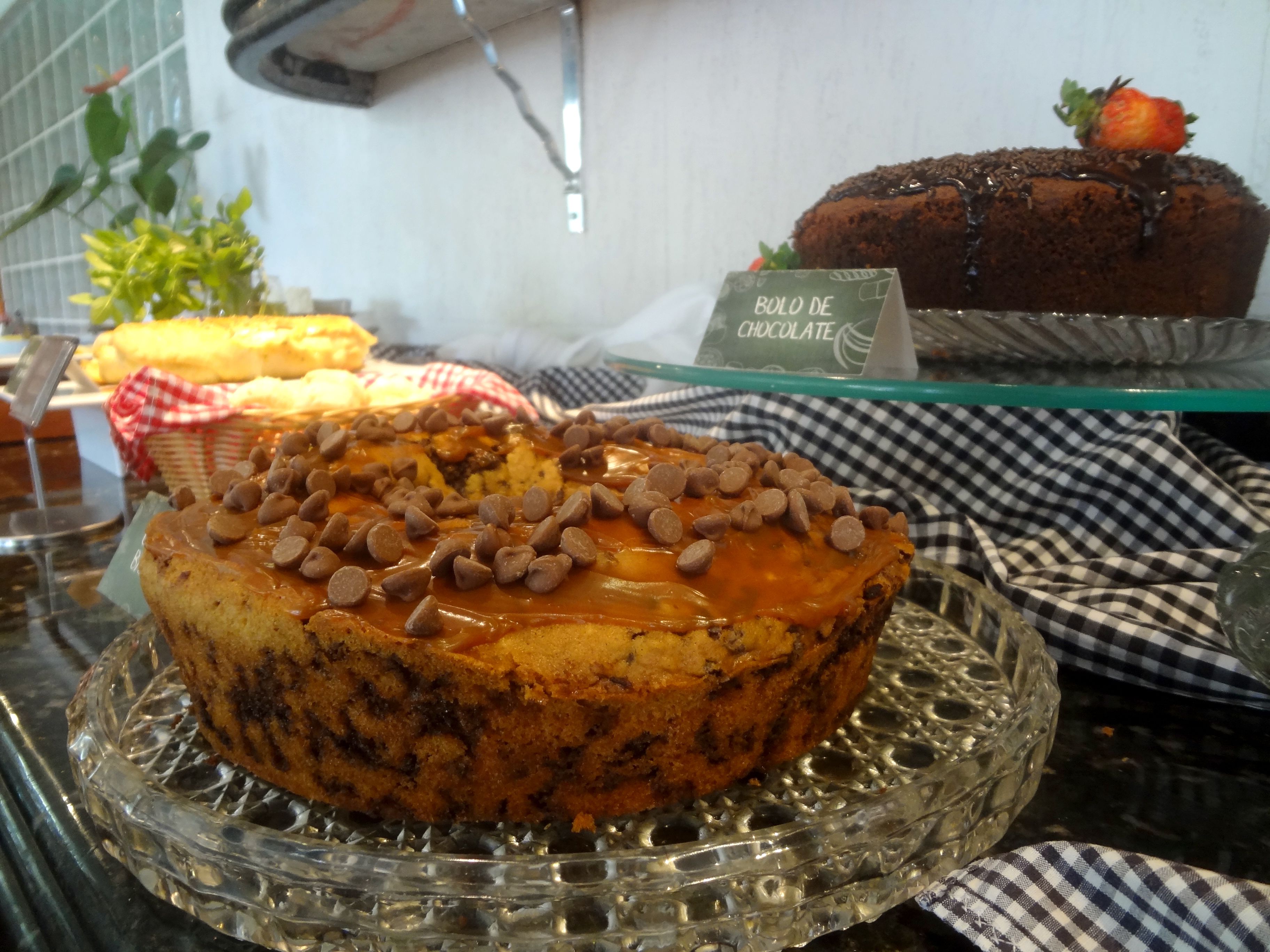 A dessert display with a chocolate cake topped with chocolate chips and a sign indicating it's a chocolate dessert.