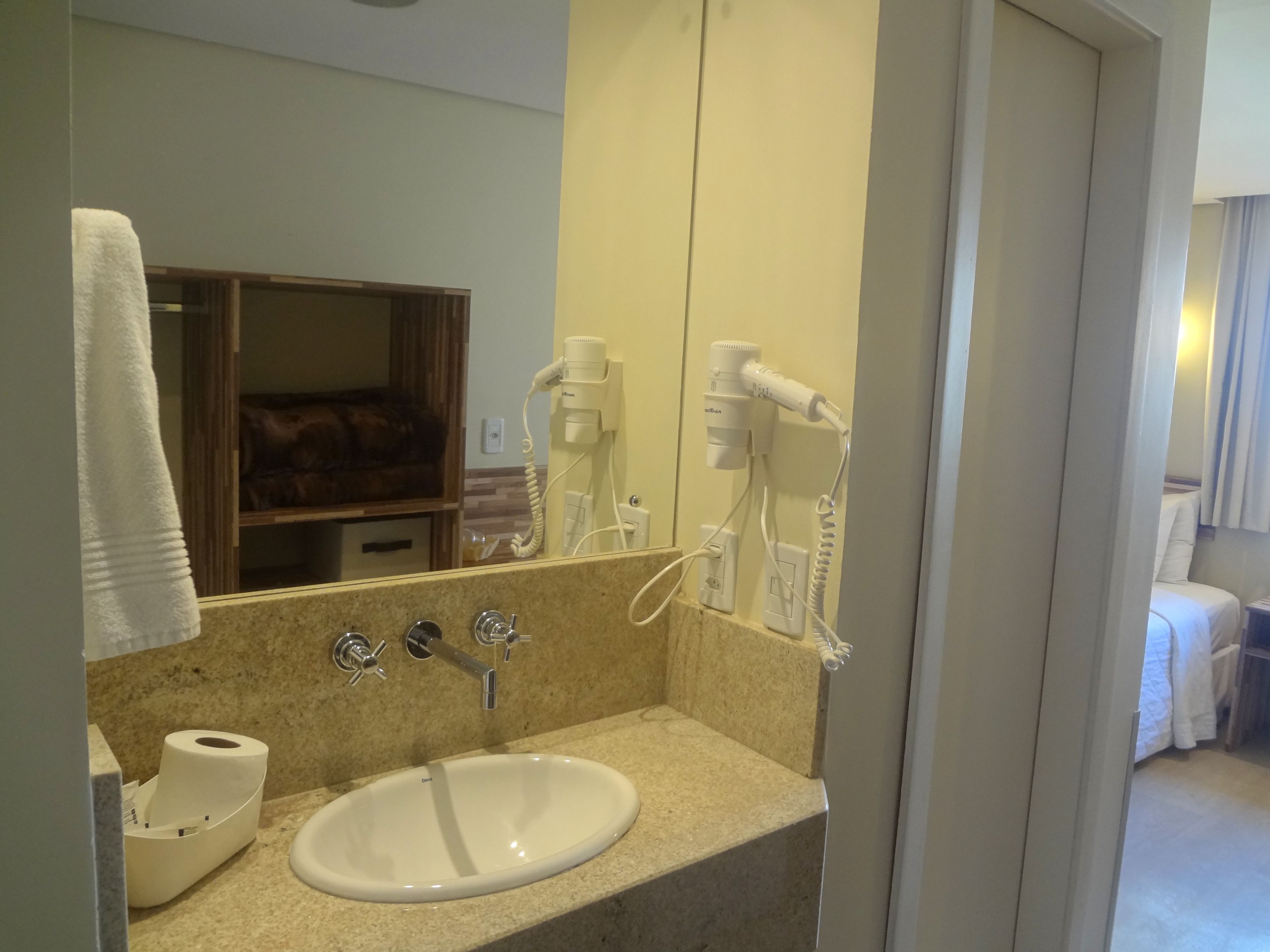 A bathroom with a sink, towel, and hairdryer.