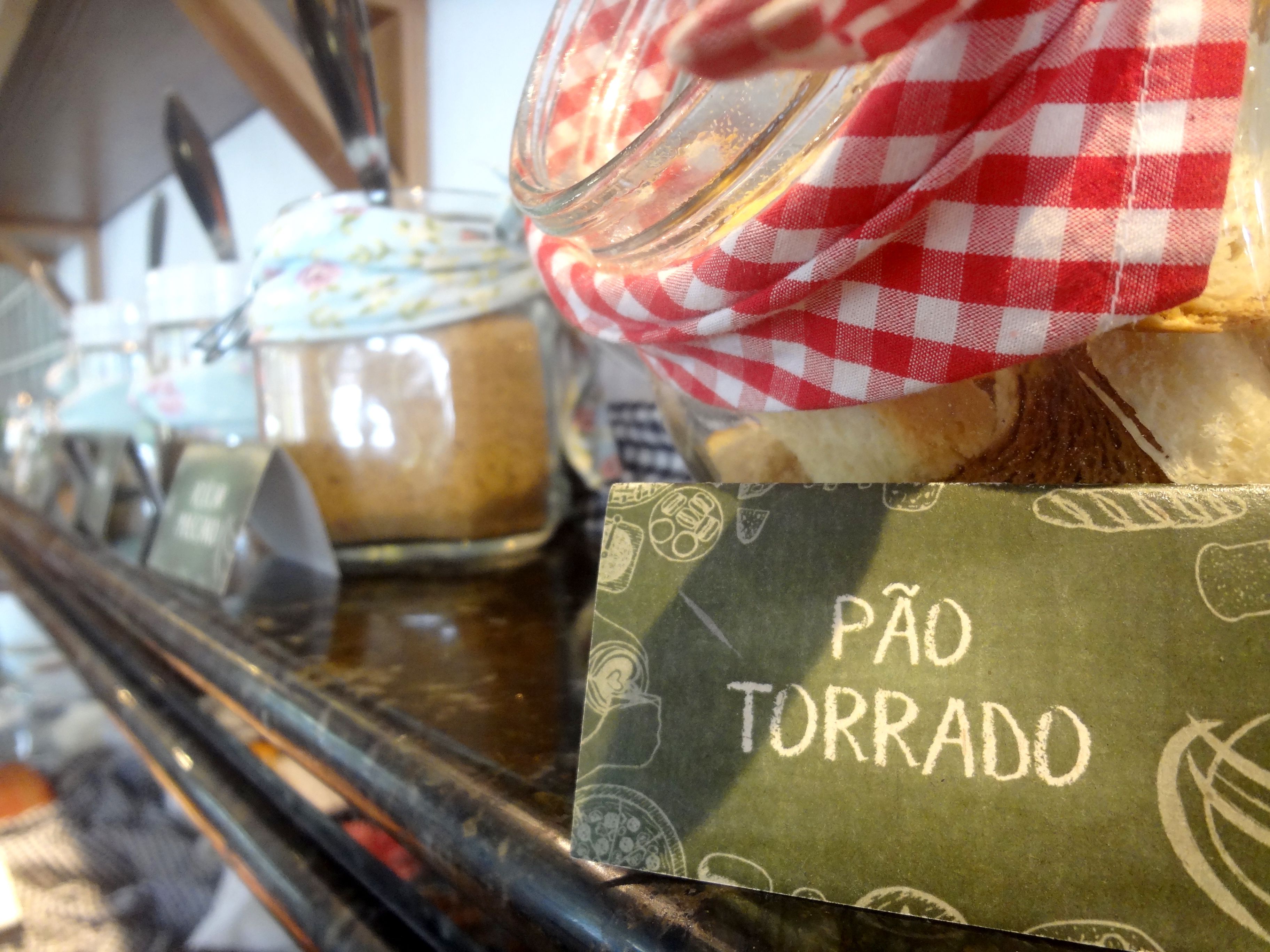 Mostrador de panadería con pan y pasteles, un mantel a cuadros y un letrero que dice 