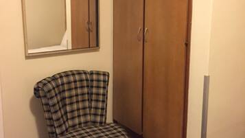 Una habitación con una silla de cuadros, un armario y un espejo en la pared.