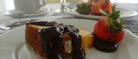 A dessert plate with a slice of cake, chocolate sauce, and a strawberry on a white plate.