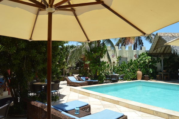 Una piscina al aire libre, sombrillas, sillones reclinables de piscina