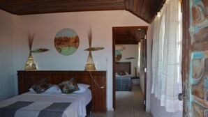 Un dormitorio con cabecera de madera, dos camas, una mesita de noche y una lámpara de pared.