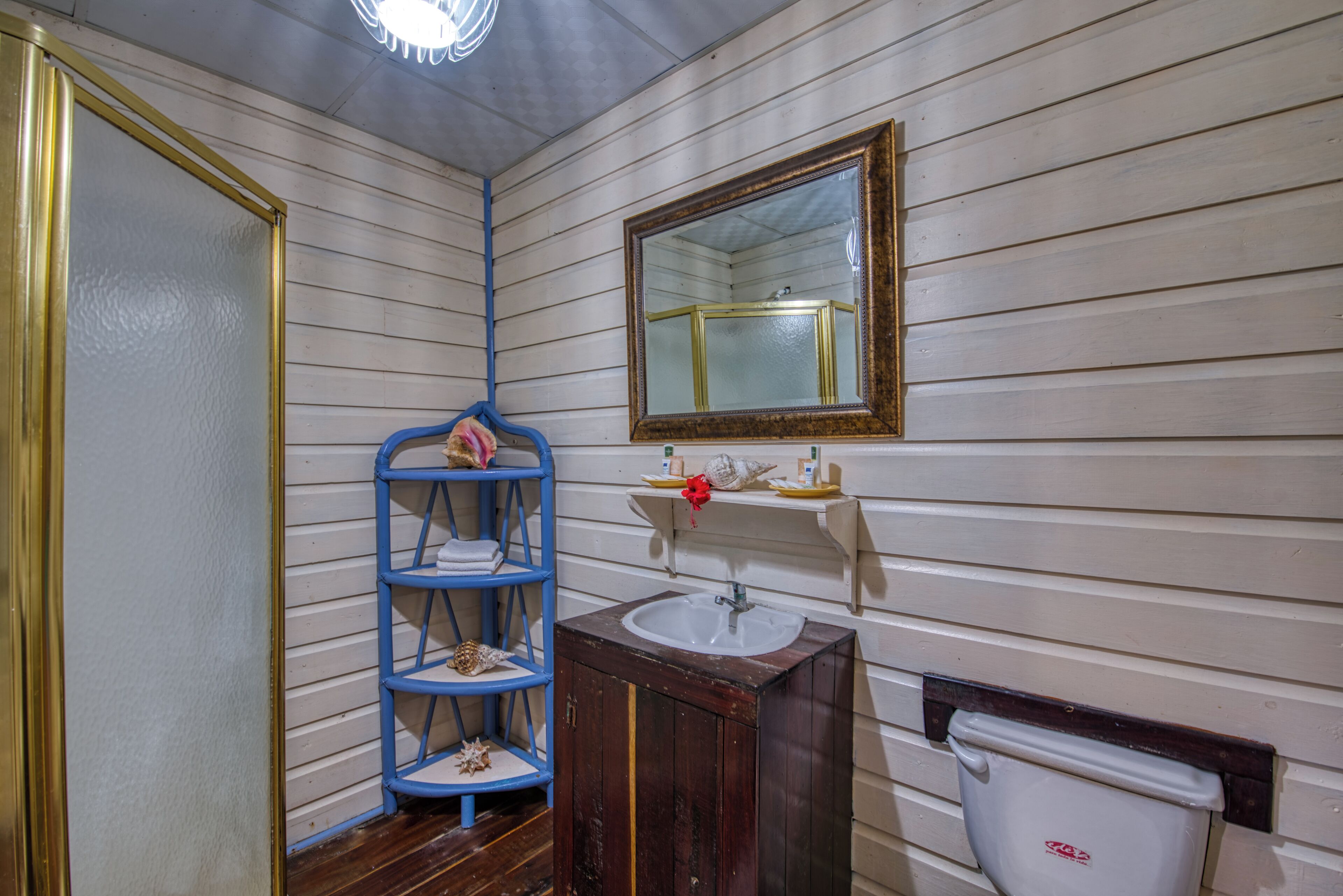 A bathroom with wooden walls, a white sink, a blue shelving unit, and a mirror.
