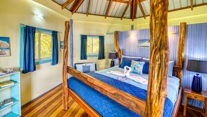 A room with a wooden four-poster bed, a bookshelf, and a desk with a lamp.