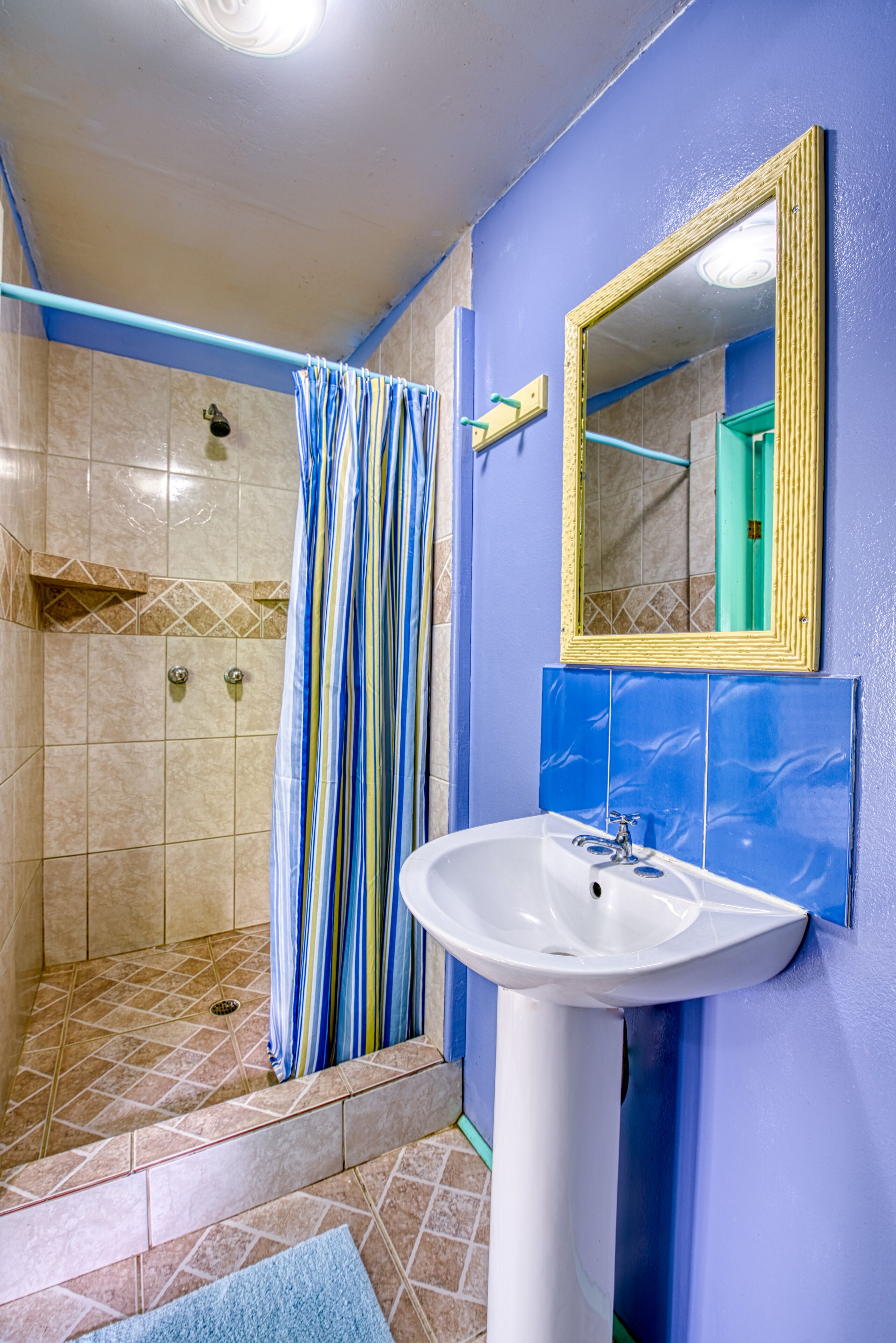 A bathroom with a shower, a sink, and a mirror.