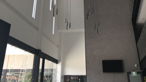 A modern interior with multiple hanging lights, large windows, and a visible door with a sign.