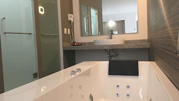 Un baño moderno con una bañera grande, una cabina de ducha de vidrio y un tocador con espejo.