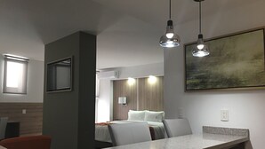 A modern hotel room with a bed, a seating area, and a dining table.