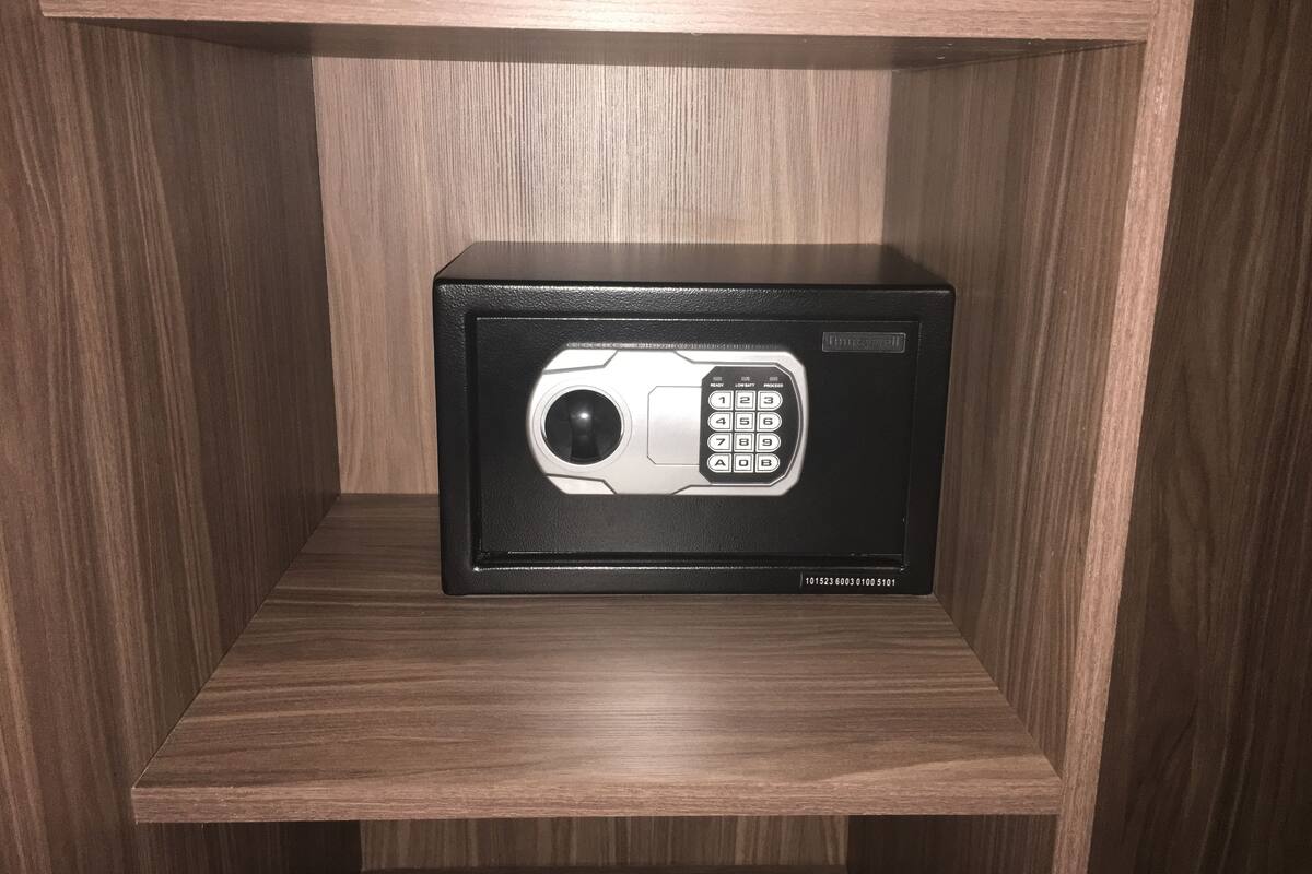 Un four à micro-ondes noir, posé sur une étagère en bois.