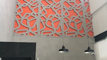 A modern interior with a decorative metal panel, a door, and pendant lighting.