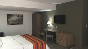 Un dormitorio con cama, escritorio, silla, televisor y armario.