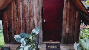 Una estructura de madera rústica con una puerta roja y un letrero que dice 'BIENVENIDO'.
