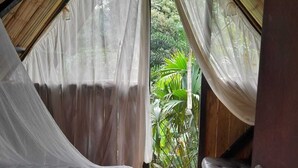 Una habitación con carpa, una cama, un banco y vistas a la vegetación.
