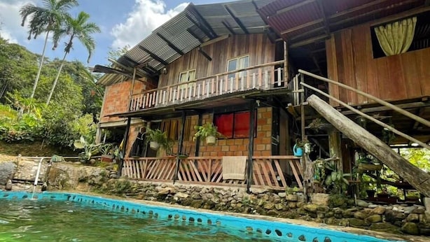 Una casa de madera con balcón, piscina y un muro de piedra.