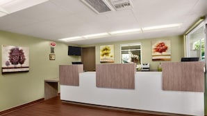 A reception area with a reception desk, a flat-screen TV, and framed artwork on the walls. - Kings Inn Anaheim (Anaheim)